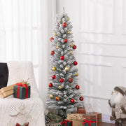 Pencil Christmas tree dressed with red and gold baubles beside gifts and an armchair