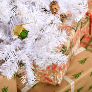 Close-up of a golden drum ornament and a pine cone on white branches