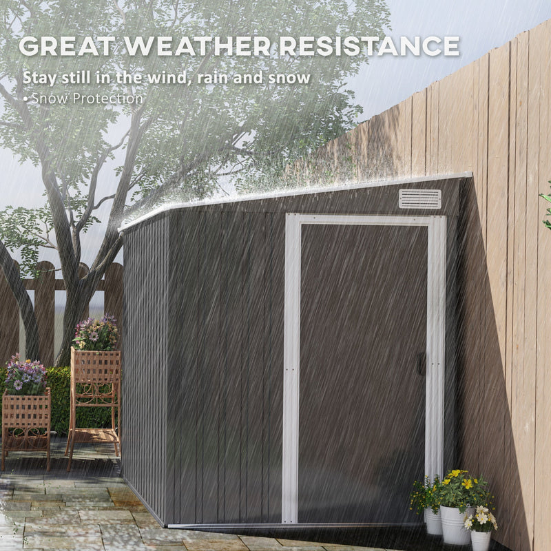 Dark grey metal shed standing in heavy rain beside a fence, showing its weather resistance