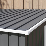 Close-up of the ribbed dark grey pent roof panels and white edge trim against a wooden fence