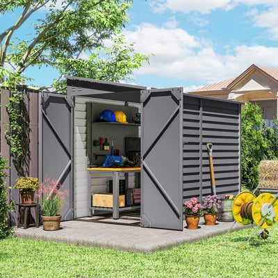 The grey lean-to shed in a garden with both doors open, showing a workbench and pegboard inside