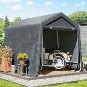 Dark grey shed on a stone base storing a motorbike beside plant pots