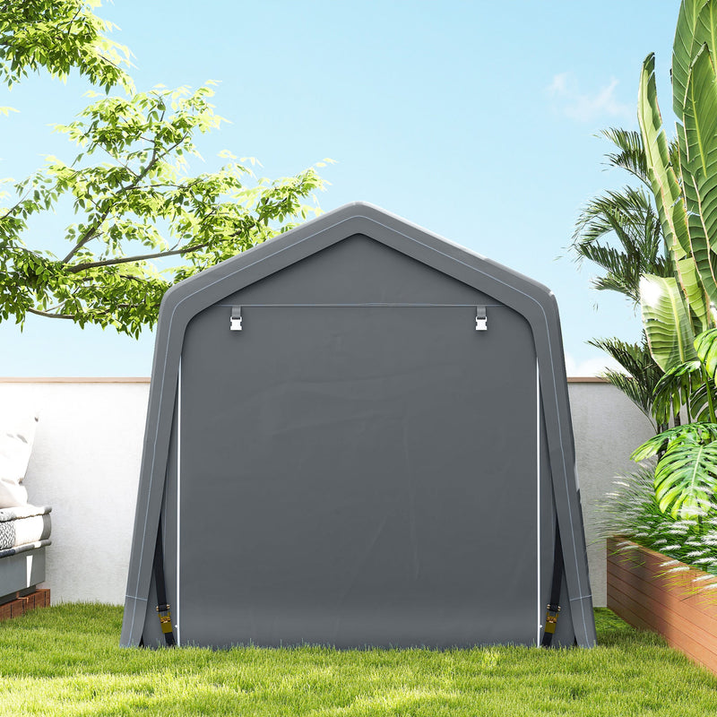 Closed end of the dark grey shed on a lawn beside a plain wall