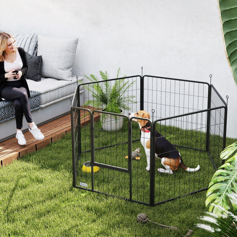 Black dog playpen set up on a garden lawn with a dog inside