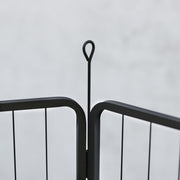 Close-up of a black steel playpen panel joint with a looped ground stake