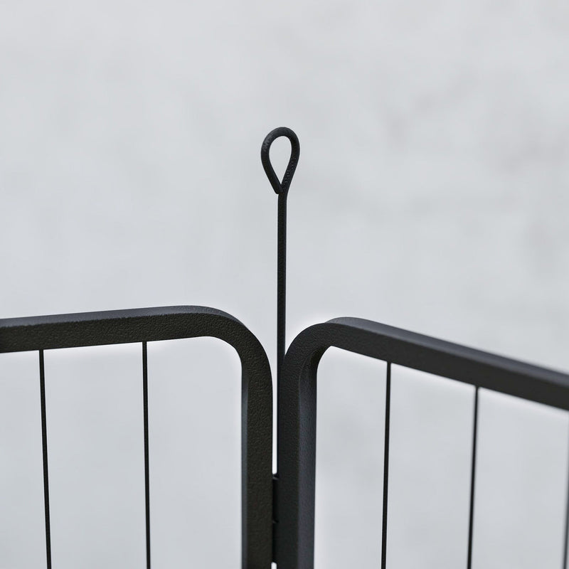 Close-up of a black steel playpen panel joint with a looped ground stake