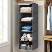 Grey hanging wardrobe organiser near a window storing rolled towels and shoes