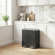 Black pedal bin standing in a marble-tiled kitchen beside white cabinets