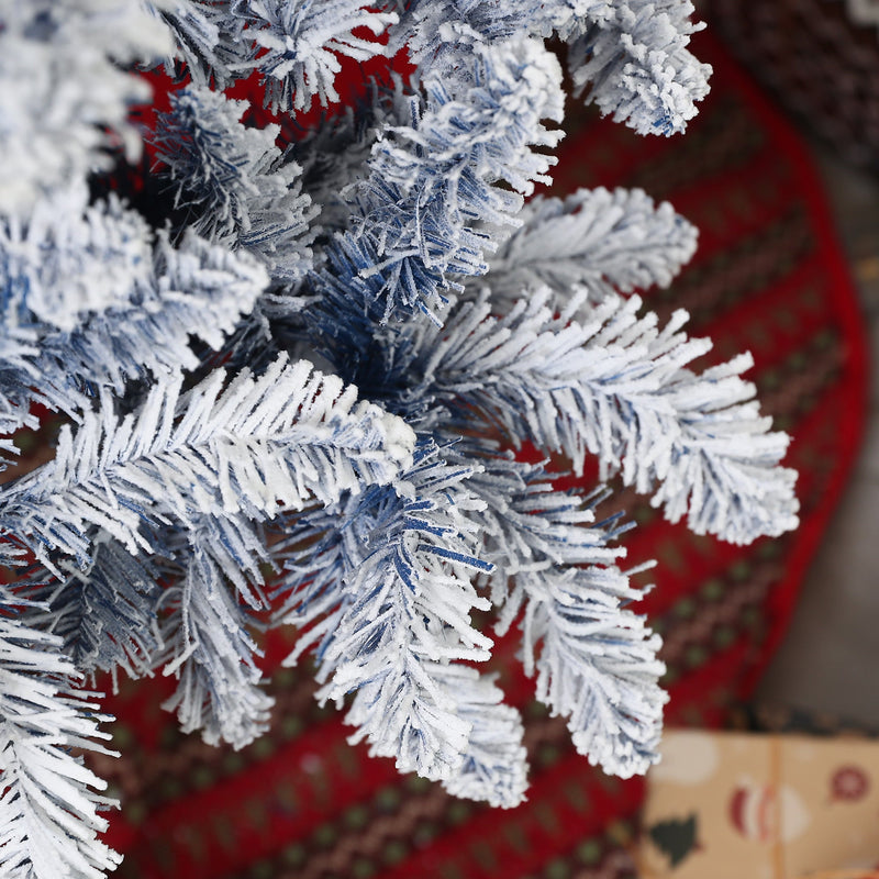 Macro of frosted blue-white branch tips over a red tree skirt