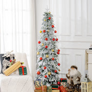Slim tree decorated with red and gold baubles beside an armchair