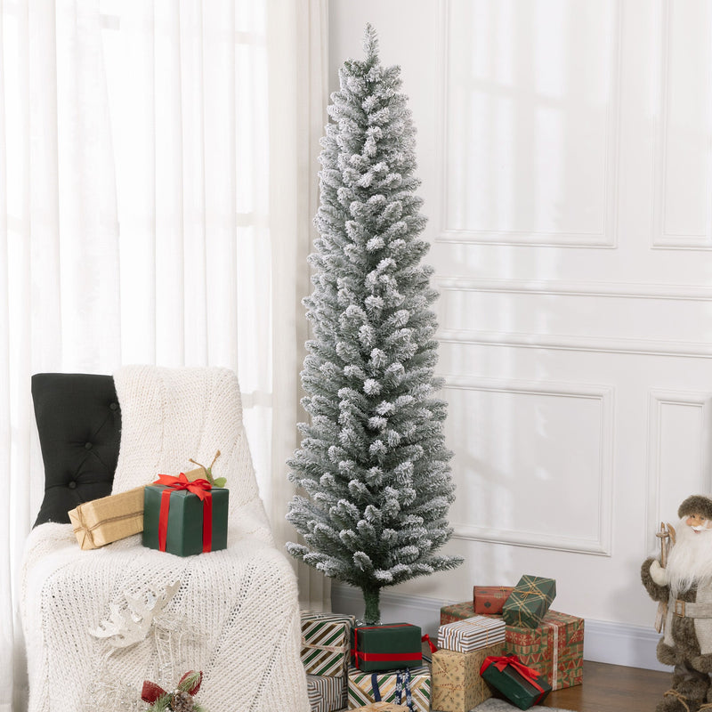 Tall snowy pencil Christmas tree in a bright room beside an armchair and wrapped gifts