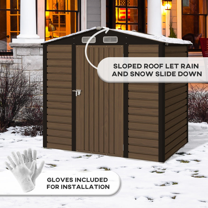 Shed standing in snow outside a lit house, with the sloped apex roof and included gloves marked
