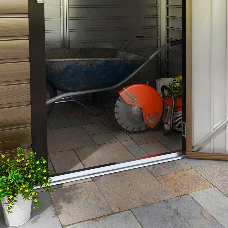 View out through the open doorway onto paving, with a wheelbarrow and disc cutter outside