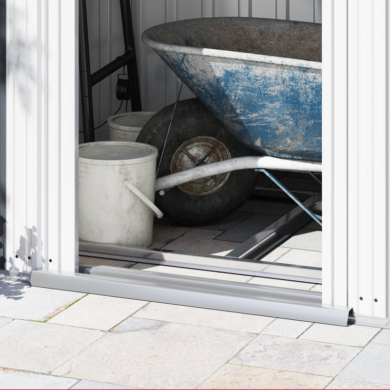Close-up of a wheelbarrow and buckets stored inside the shed at the door threshold rail