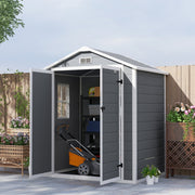 Grey plastic shed on a patio with one door open, a mower and shelves inside
