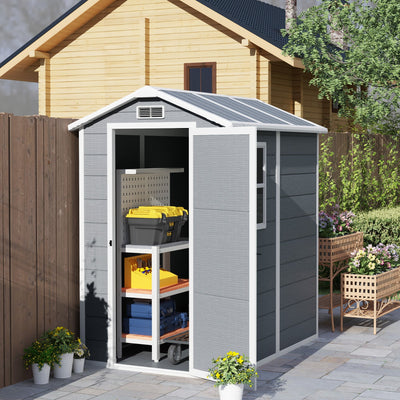 Plastic garden shed beside a timber cabin with the door open showing shelves of tools