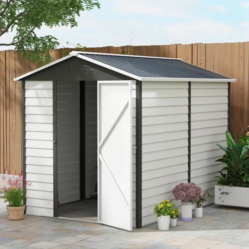 White metal garden shed with apex roof beside a wooden fence and potted flowers
