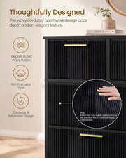 Close-up of fluted black corduroy drawer fronts with a gold handle and a hand on the fabric