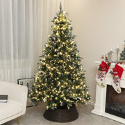 Pre-lit 7ft Christmas tree with warm white lights on a woven collar beside a fireplace with stockings