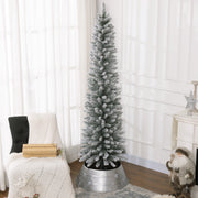 Tall snowy pencil Christmas tree in a silver tree skirt beside an armchair in a bright room