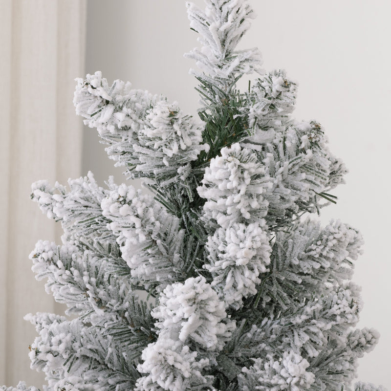 Close-up of white flocked branch tips and green needles at the top of the tree