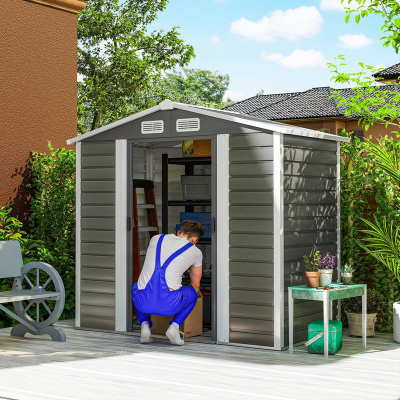 Man loading a box into the open 7x4ft apex metal shed with shelving inside