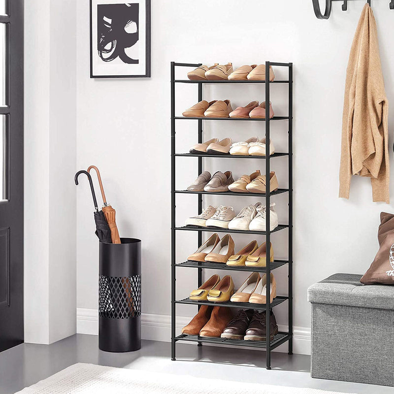 The shoe rack in a white hallway holding 16 pairs of shoes, beside an umbrella stand and storage bench