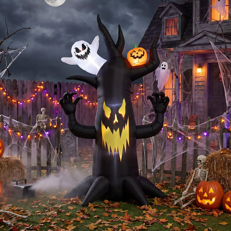 Spooky tree inflatable displayed in a fenced garden with skeleton props and fairy lights