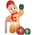 Inflated orange gingerbread man in a Santa hat holding a gift beside a candy cane and two presents