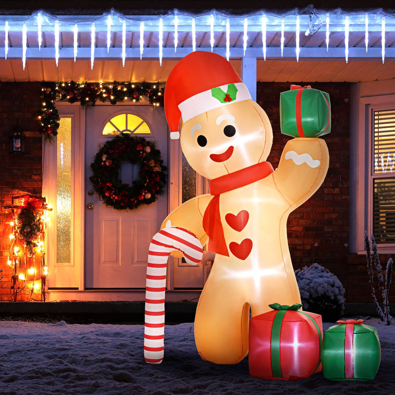 Lit gingerbread man inflatable outside a front door with a wreath and icicle lights at night