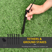 Six black ground stakes and tethers, with a hand pushing a tether onto a stake on grass