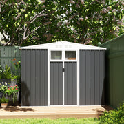 Dark grey shed closed on garden decking in front of a dark green fence and flowering shrubs