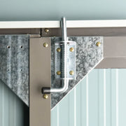 Close-up of the galvanised slide bolt and corner bracket at the top of the door