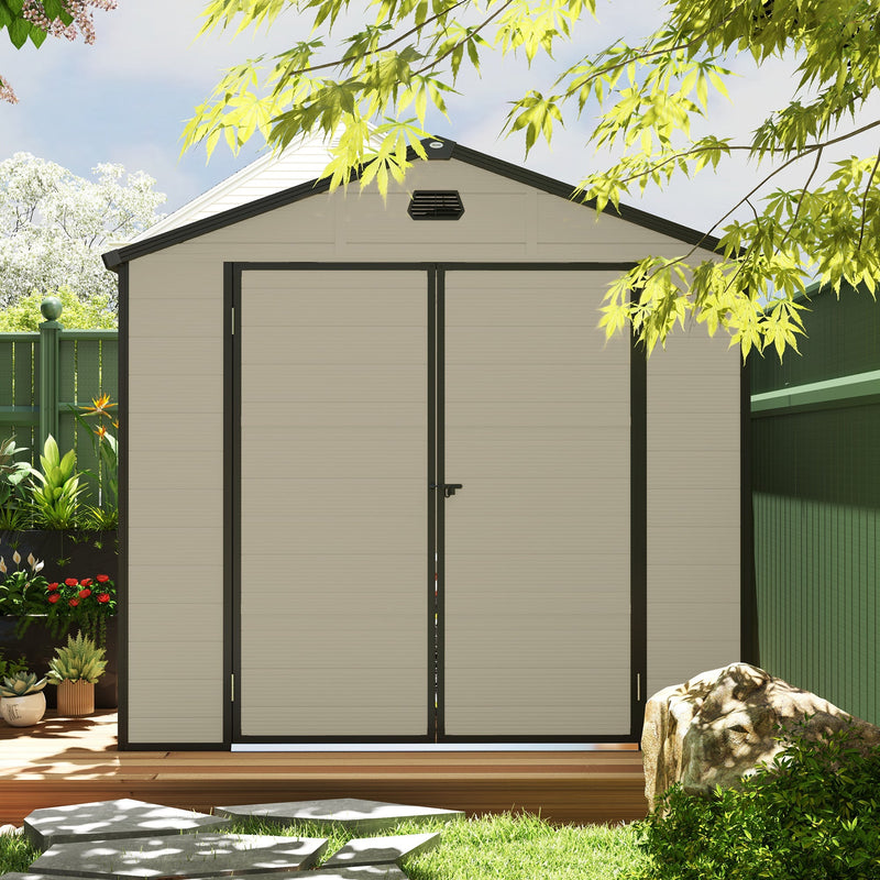 Front view of the closed cream white shed in a garden, showing the double doors and gable vent