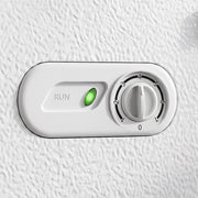 Close-up of the white chest freezer's temperature dial and green run indicator