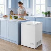 White chest freezer beside a kitchen island while a woman prepares a salad