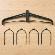 Arch top frame and four U-shaped metal ground stakes laid out on a wood floor
