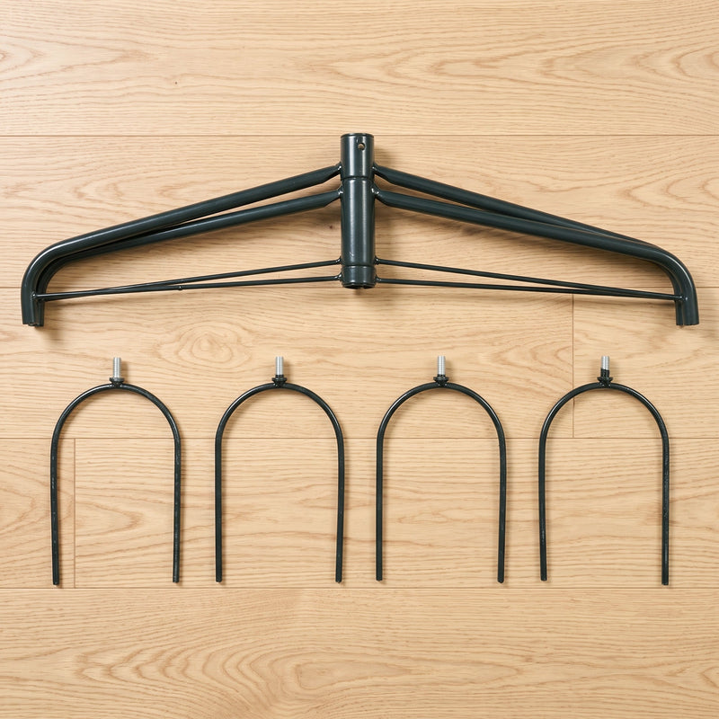 Arch top frame and four U-shaped metal ground stakes laid out on a wood floor