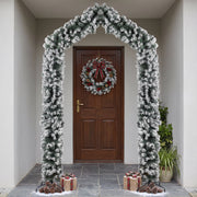 Flocked Christmas arch framing a front door with a red berry wreath