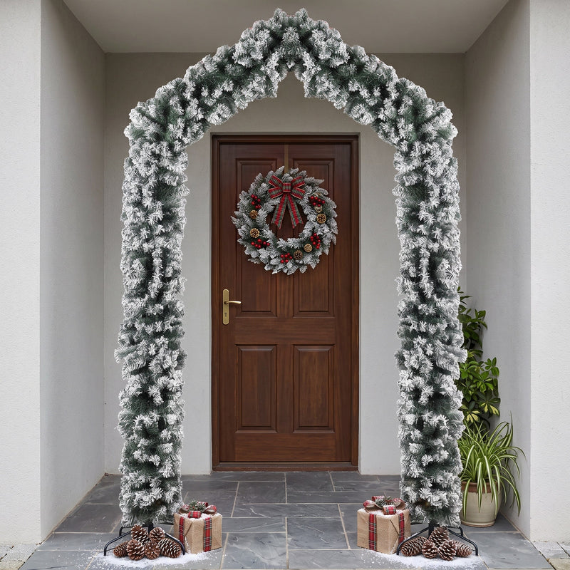 Flocked Christmas arch framing a front door with a red berry wreath