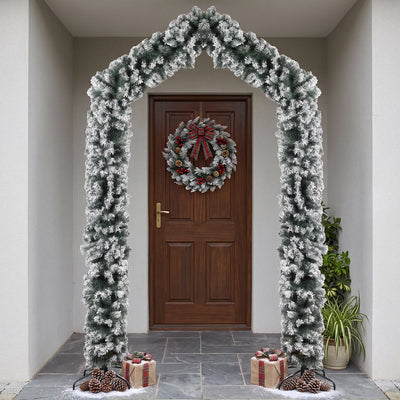 Flocked Christmas arch framing a front door with a red berry wreath