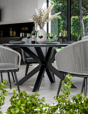 Aspen round ceramic dining table and grey rope chairs arranged on a patio