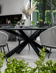 Aspen oval ceramic dining table and grey rope chairs arranged on a patio