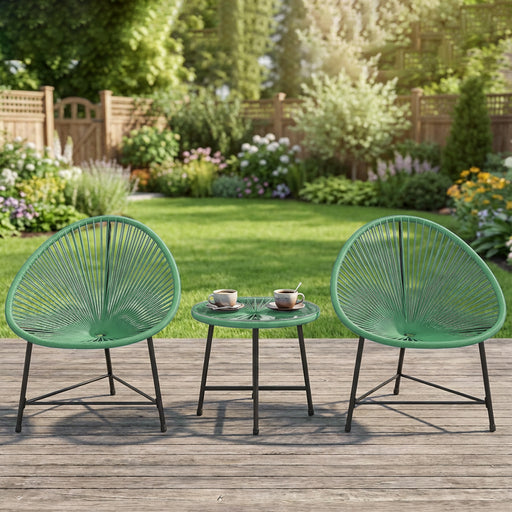 Two green patio chairs with a small table on a wooden deck in a garden setting.
