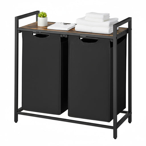 Black laundry sorter with wooden top holding folded clothes and a plant on a white background