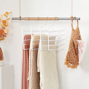 White trouser hangers holding folded trousers on a wardrobe rail by Songmics