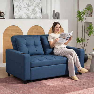 Woman reading on the dark blue sofa bed styled in a living room with plants