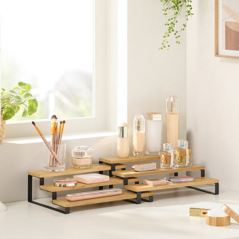 Black-framed bamboo rack holding make-up brushes and skincare bottles on a sunlit windowsill