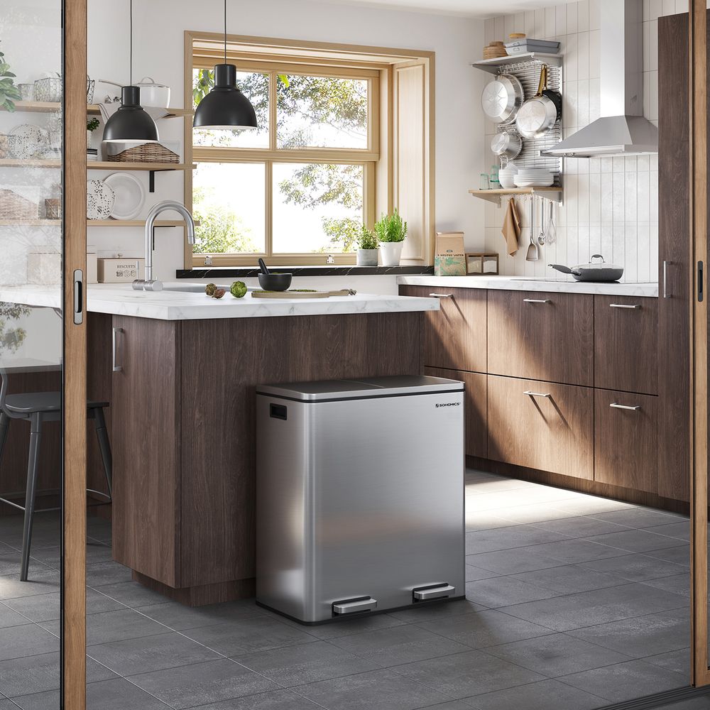 Modern kitchen with wooden cabinets, a window, and a stainless steel trash bin.