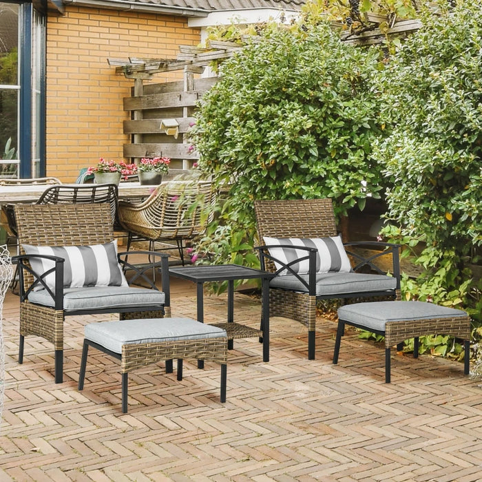 Image of a rattan patio furniture set consisting of 2 khaki coloured armchairs with grey seat cushions, 2 footstools and a coffee table with a shelf